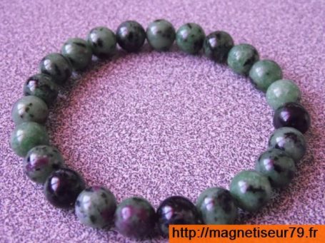 Bracelet en perles vertes et noires, sur fond violet.