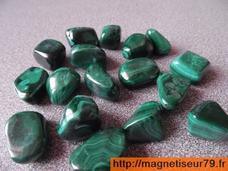 Gros blocs de malachite verte brillants disposés sur une surface grise.